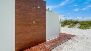A modern building with a wooden facade, a metal door, and a paved entrance area. - Luxury Beachfront on the Sand of Gulf of Mexico (Anna Maria)