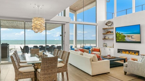 A spacious living area with a large dining table, comfortable seating, a fireplace, and a large TV. - Luxury Beachfront on the Sand of Gulf of Mexico (Anna Maria)