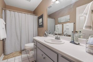 Un baño con lavamanos blanco, inodoro y cortina de ducha.