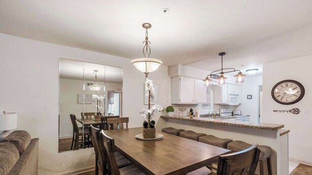 A modern kitchen with a central island, a dining area with a large table and chairs, and a living area with a sofa. - Bunker Ridge Rendezvous - Branson - Condo in Pointe Royale (Branson)