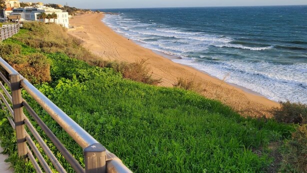 A coastal walkway with a metal railing, leading to a sandy beach and the ocean. - House (Albufeira)