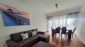 A living room with a brown sectional sofa, a coffee table, and a dining area with a table and chairs. - House (Albufeira)