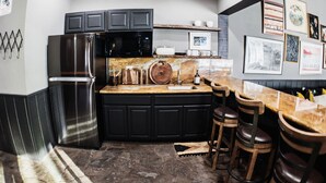 A modern kitchen with black cabinets, a stainless steel refrigerator, a microwave, and a wooden island with bar stools. - Chamonix #70 - Near Yearly Outdoor Activities! (Mammoth Lakes)