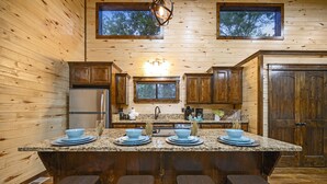 Una cocina con paredes de madera, encimeras de granito y una isla central con taburetes.