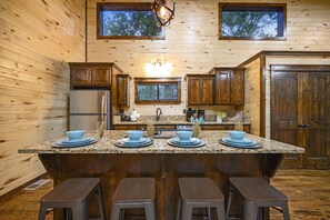 Una cocina con paredes de madera, encimeras de granito y una isla central con taburetes.