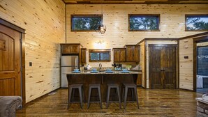 Cocina de cabaña de madera con una isla central, taburetes de bar y encimera de piedra.
