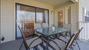 En overdækket terrasse med et glasbord og stole, skydedøre i glas samt en lille potteplante.