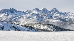 Eine verschneite Berglandschaft mit zerklüfteten Gipfeln und einem bewaldeten Tal.
