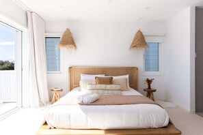 A bedroom with a large bed, a wooden headboard, and a view of the outdoors.