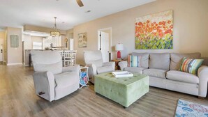 A living room with a beige sofa, a green ottoman, and a ceiling fan. - Lakefront Sanctuary - Table Rock Lake Adventures (Branson)