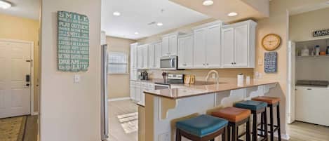 A kitchen with white cabinets, a microwave, and a clock on the wall.