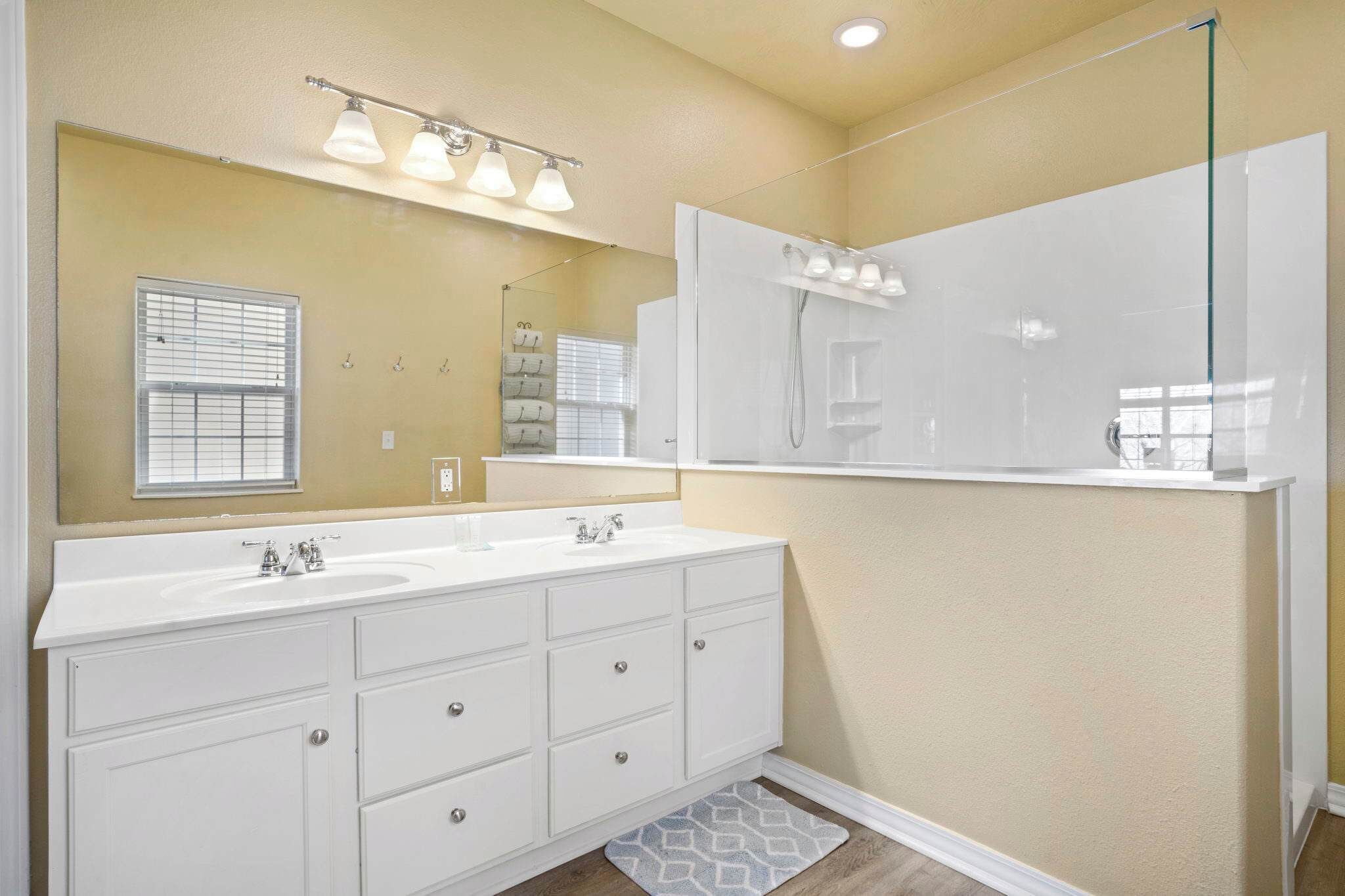 A bathroom with two sinks, a large mirror, and a shower.