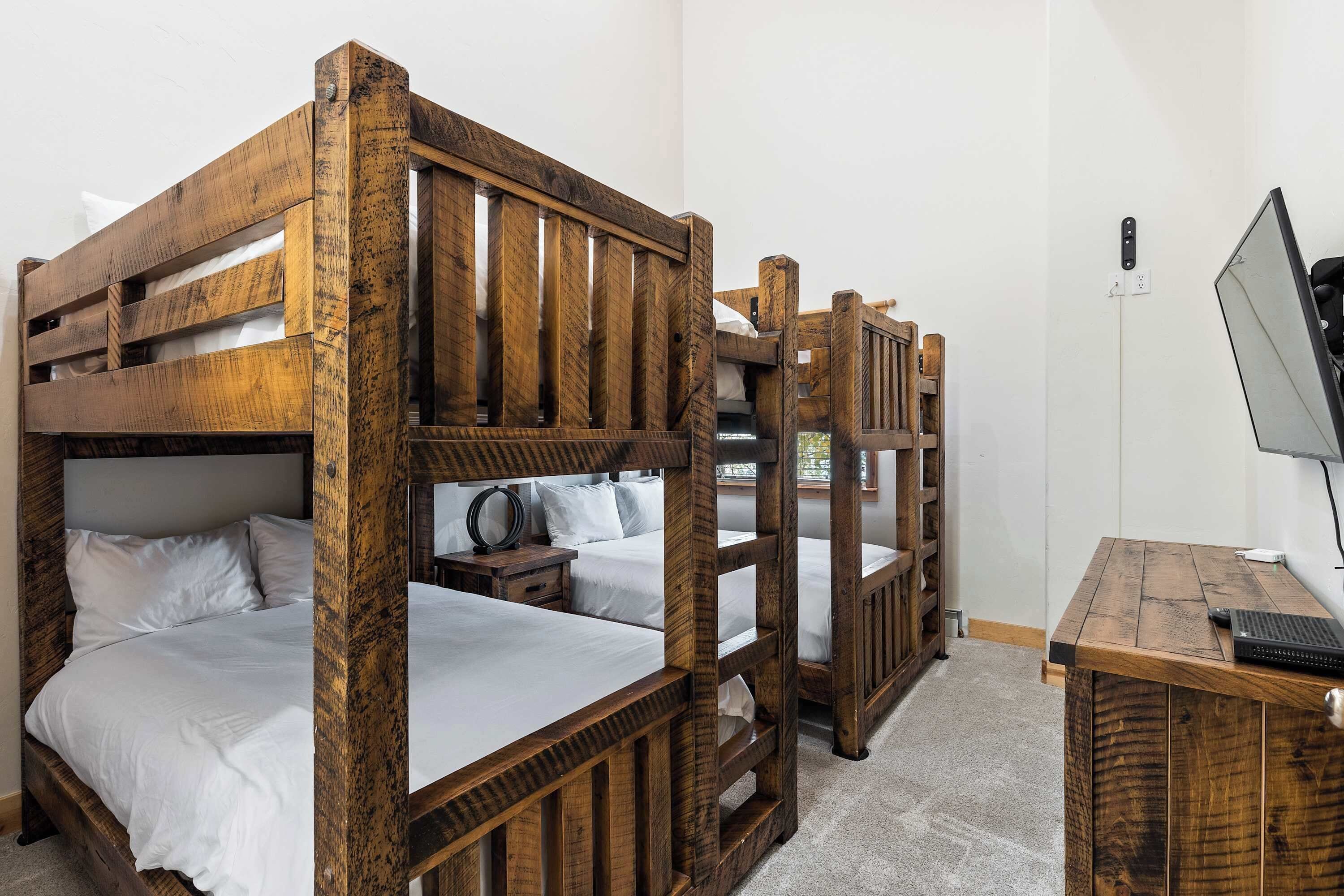 A bunk bed room with a wooden desk and a computer.