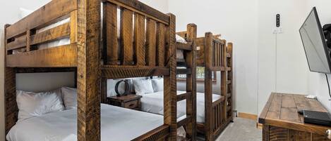 A bunk bed room with a wooden desk and a computer.