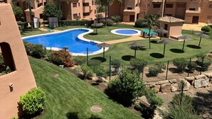 A resort with multiple swimming pools, well-maintained lawns, and palm trees.