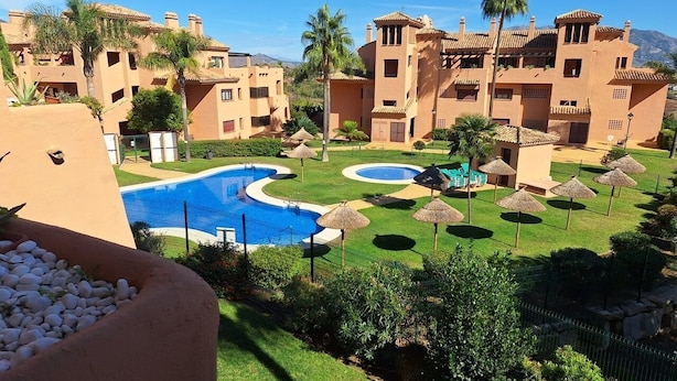 A resort with multiple buildings, a central swimming pool, and well-maintained lawns.