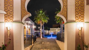 An ornate entrance with a cobblestone pathway, palm trees, and a fountain. - Vila Origens Boutique Hotel Albufeira (Albufeira)