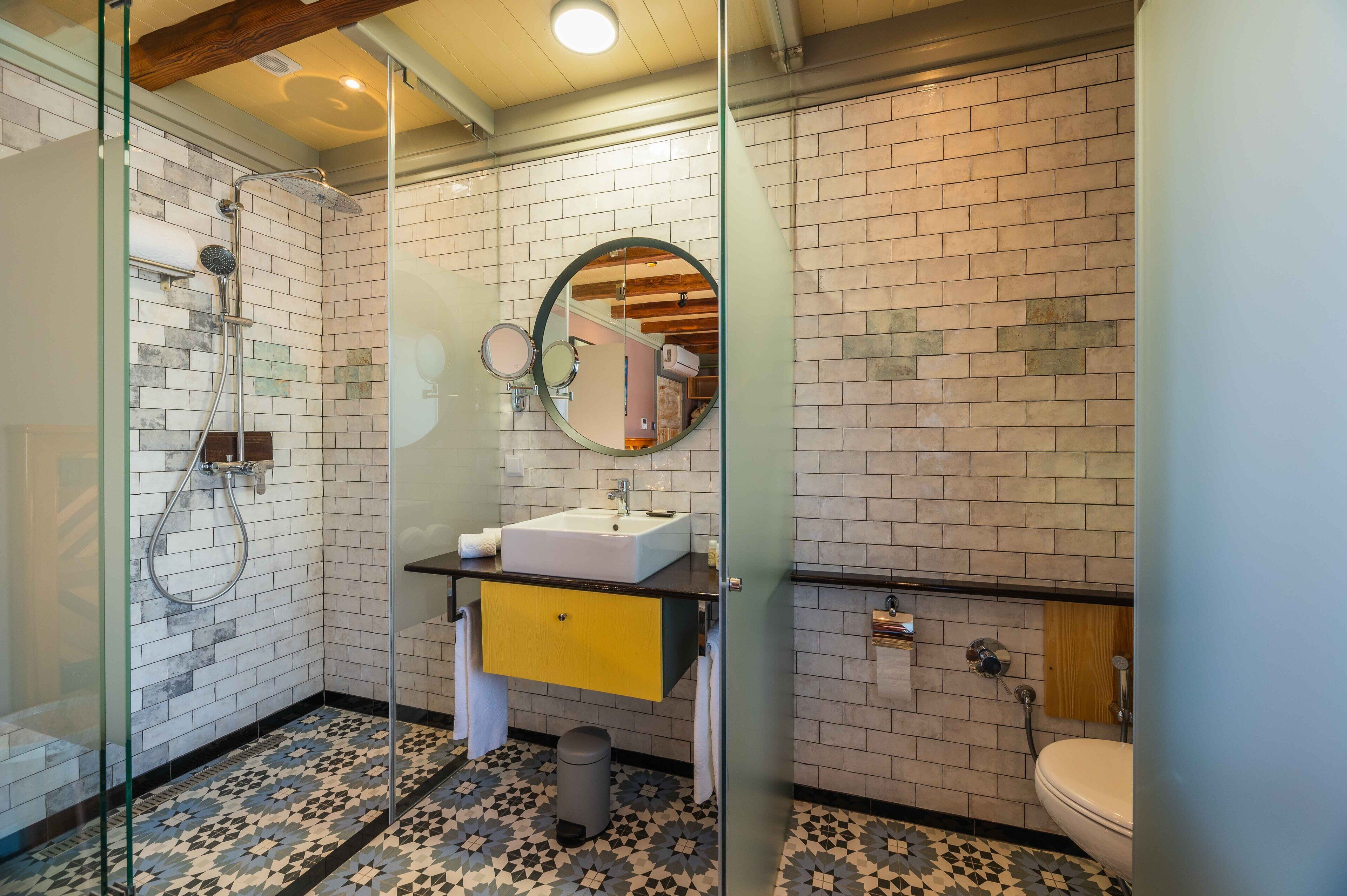 A bathroom with a glass-enclosed shower, a sink with a mirror above it, and a toilet.