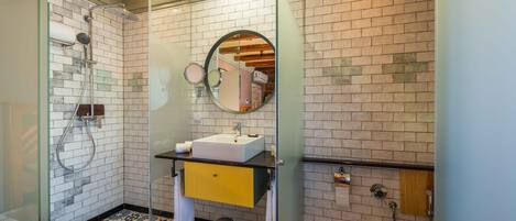 A bathroom with a glass-enclosed shower, a sink with a mirror above it, and a toilet.