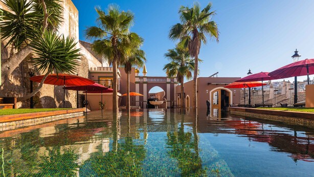 A pool area with palm trees, umbrellas, and a clear blue sky. - Vila Origens Boutique Hotel Albufeira (Albufeira)