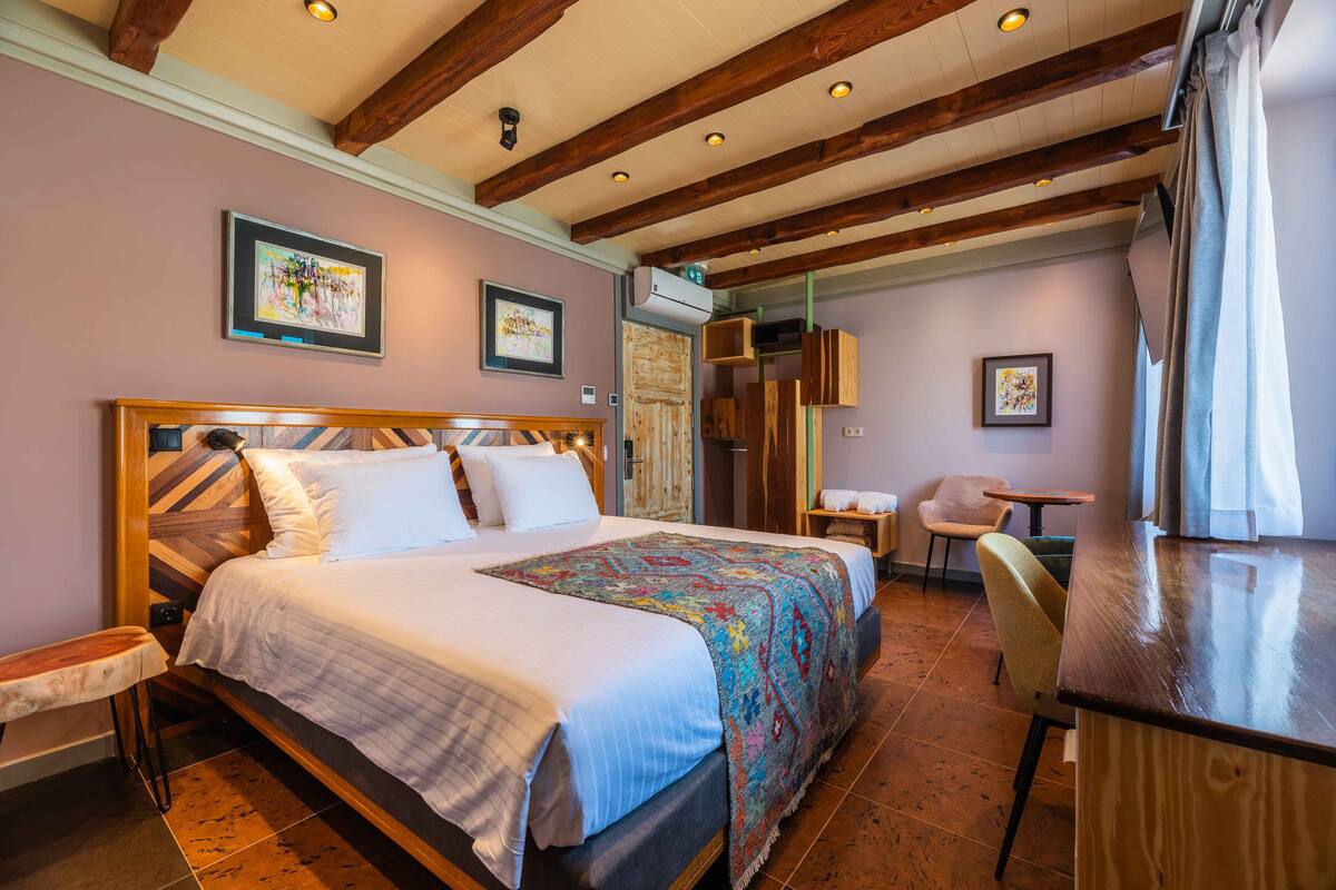 Un dormitorio con una cama grande, vigas de madera y un pequeño escritorio con silla.
