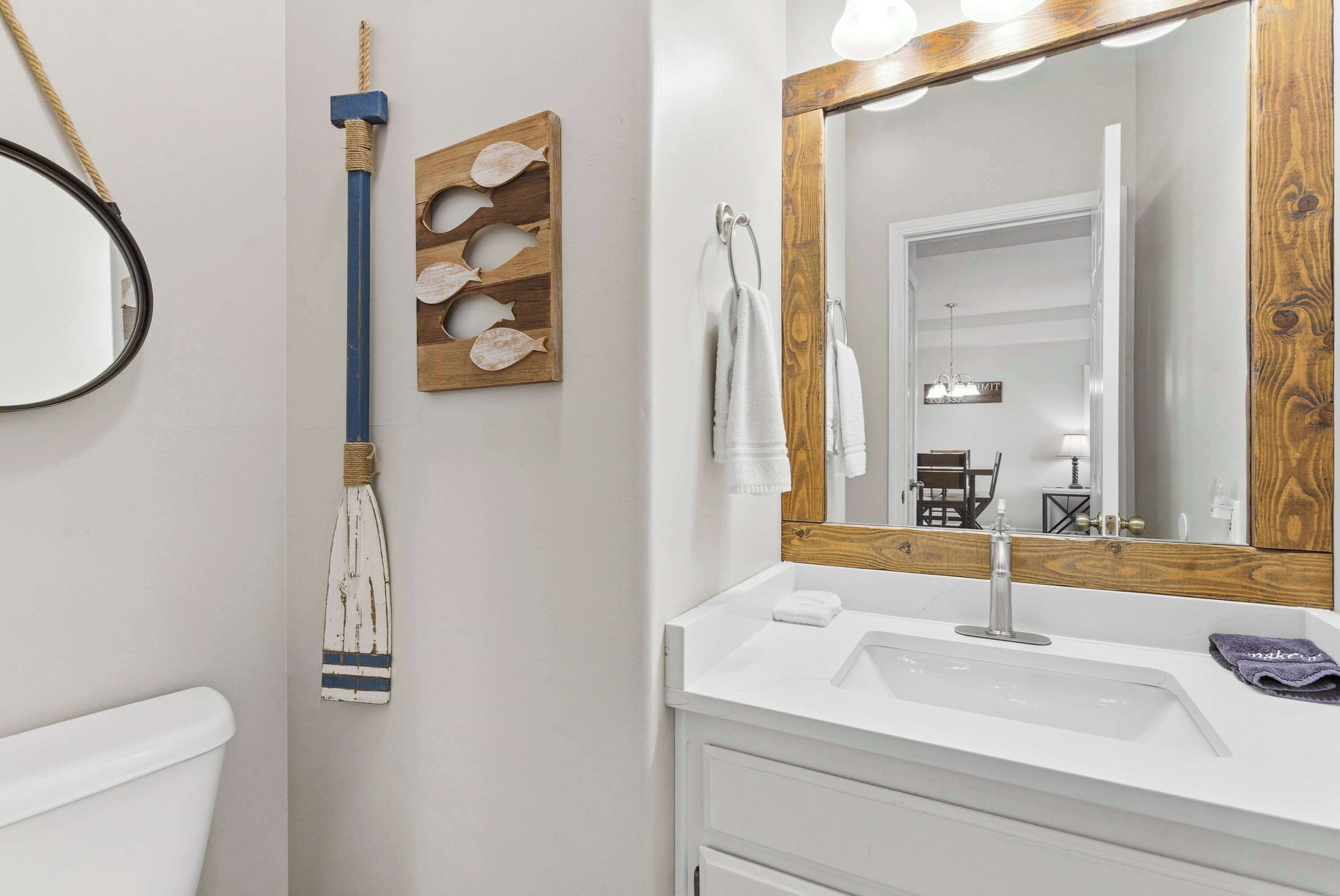 Une salle de bain avec un lavabo blanc, un miroir à cadre en bois et un porte-serviettes.