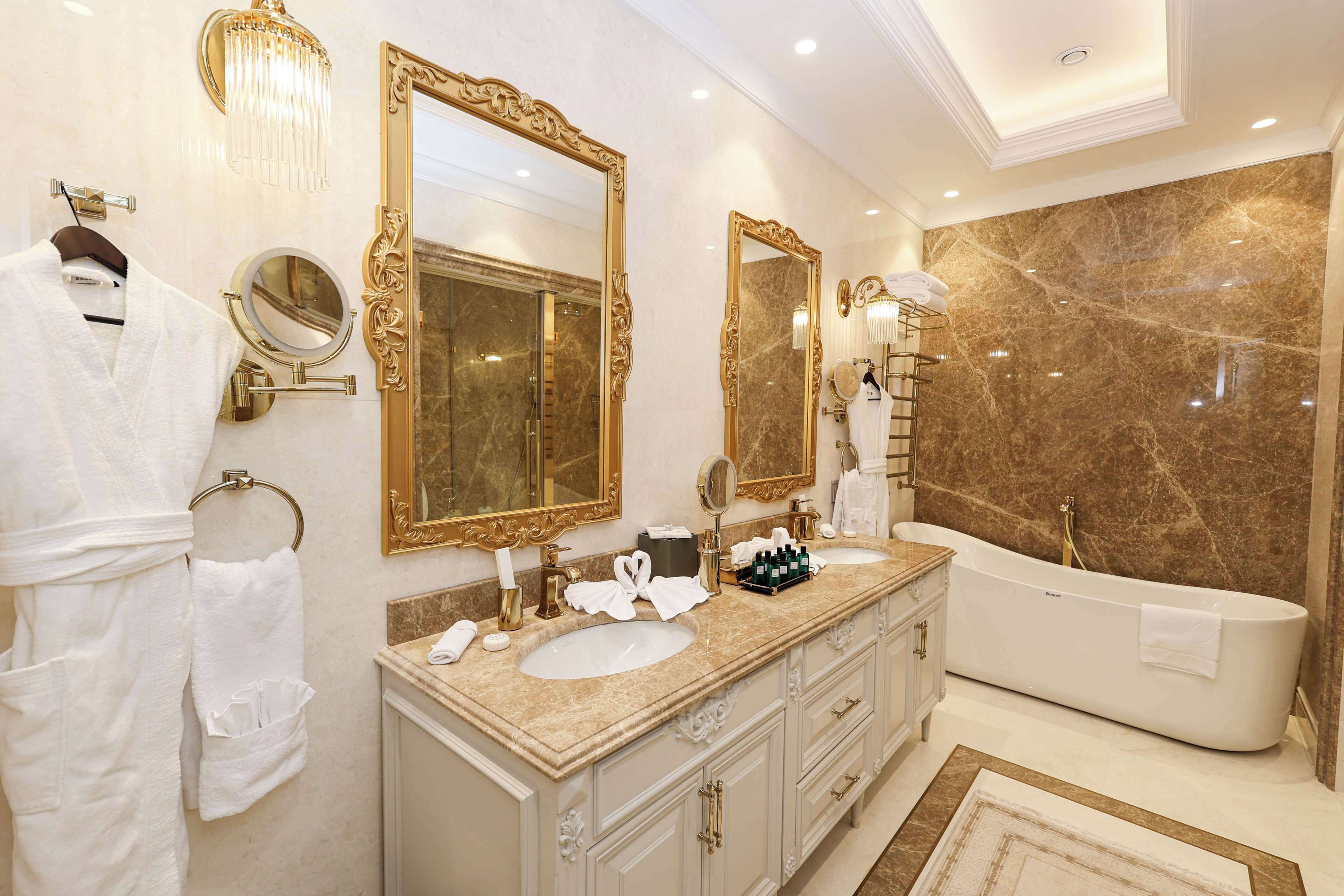 Een luxe badkamer met twee wastafels, een grote spiegel en een vrijstaand bad.