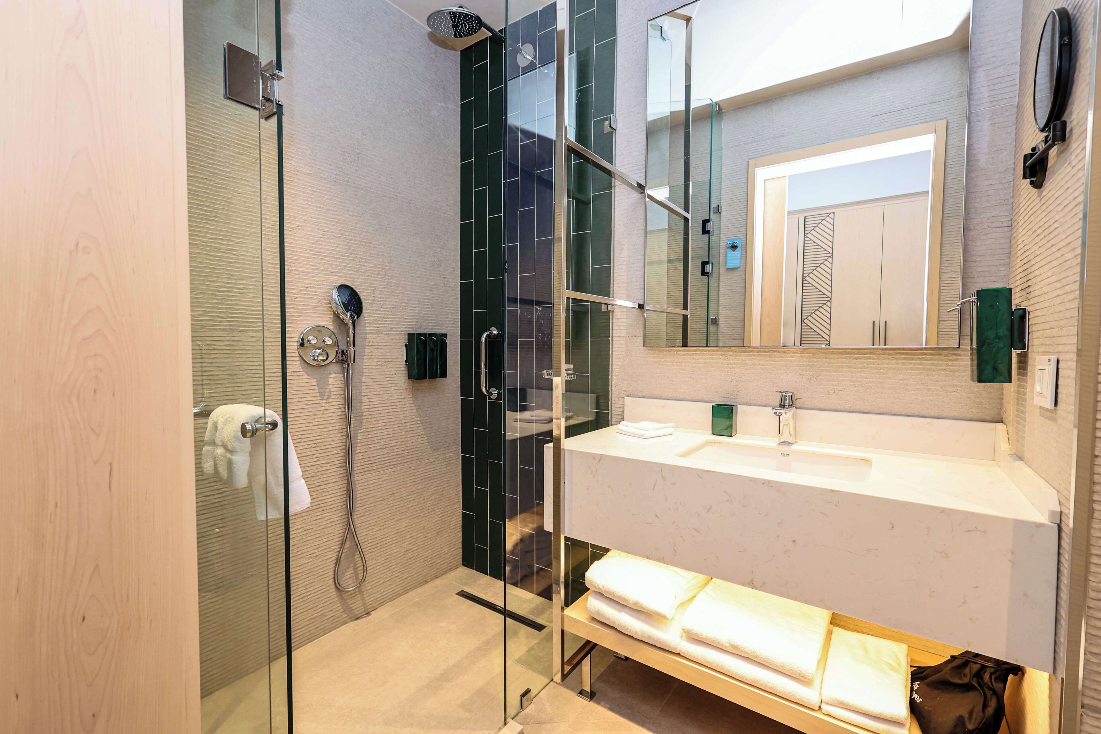 Een moderne badkamer met een douchecabine van glas, een wit wastafelmeubel en een spiegel erboven.