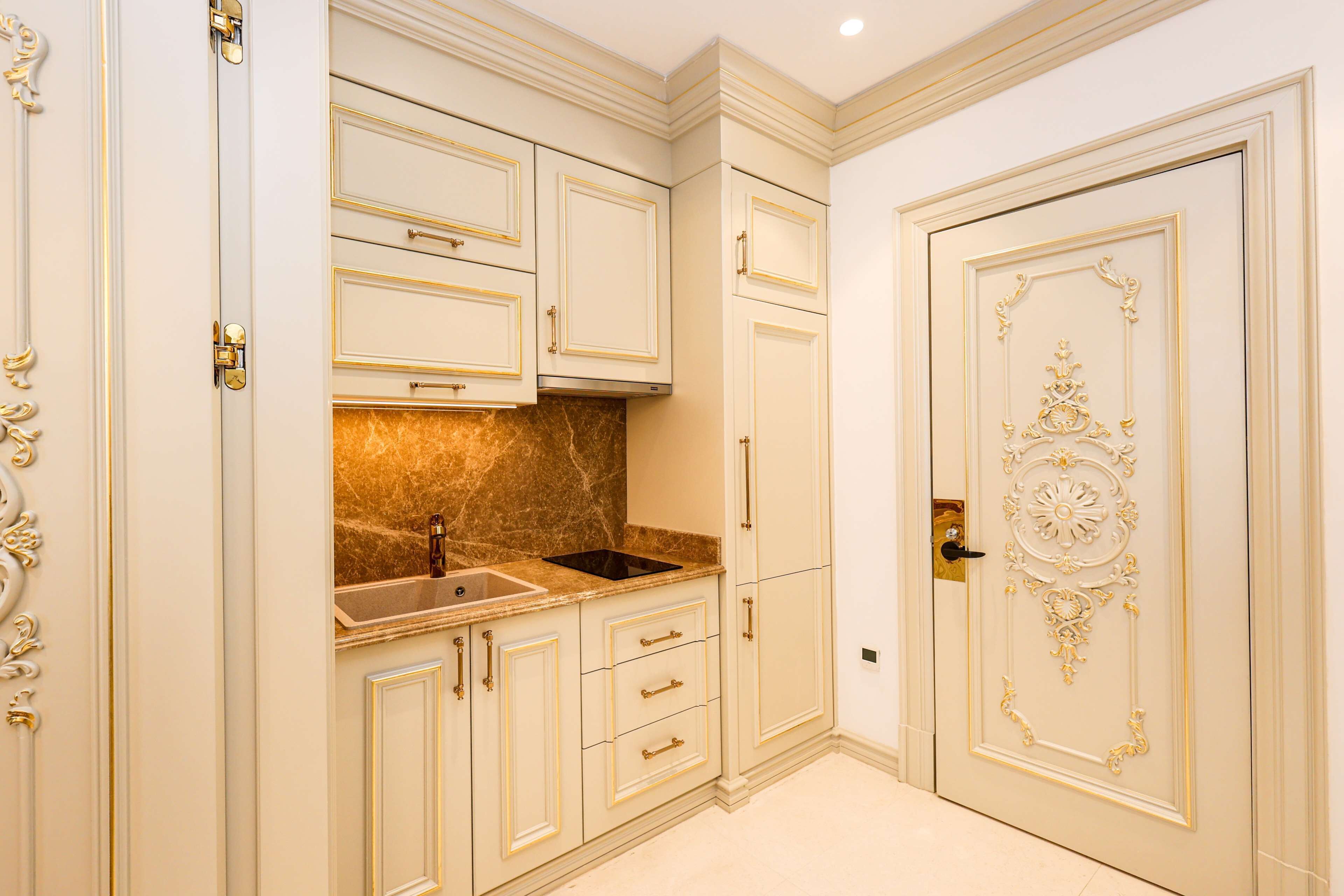 A kitchen with white cabinetry, a marble countertop, and a decorative door.