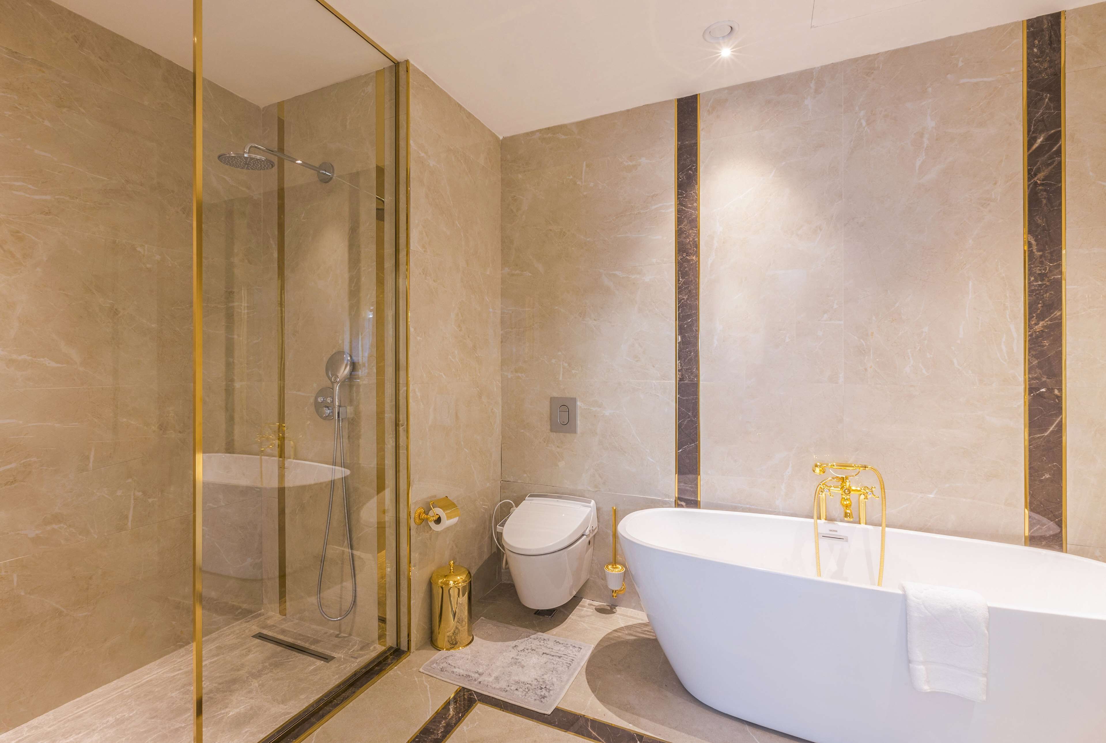 Een moderne badkamer met een glazen douchecabine, een vrijstaand bad en een toilet.