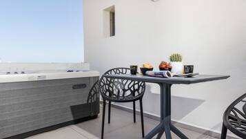 A modern outdoor seating area with a table and chairs, a hot tub, and a small potted plant.