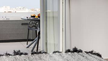 Un balcone moderno con tavolo e sedie, vista sulla città e un tappeto decorato.