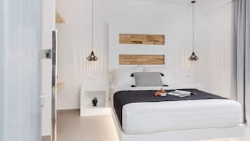 Un dormitorio moderno con una cama grande, dos lámparas colgantes, una mesita de noche pequeña y un panel de madera montado en la pared.