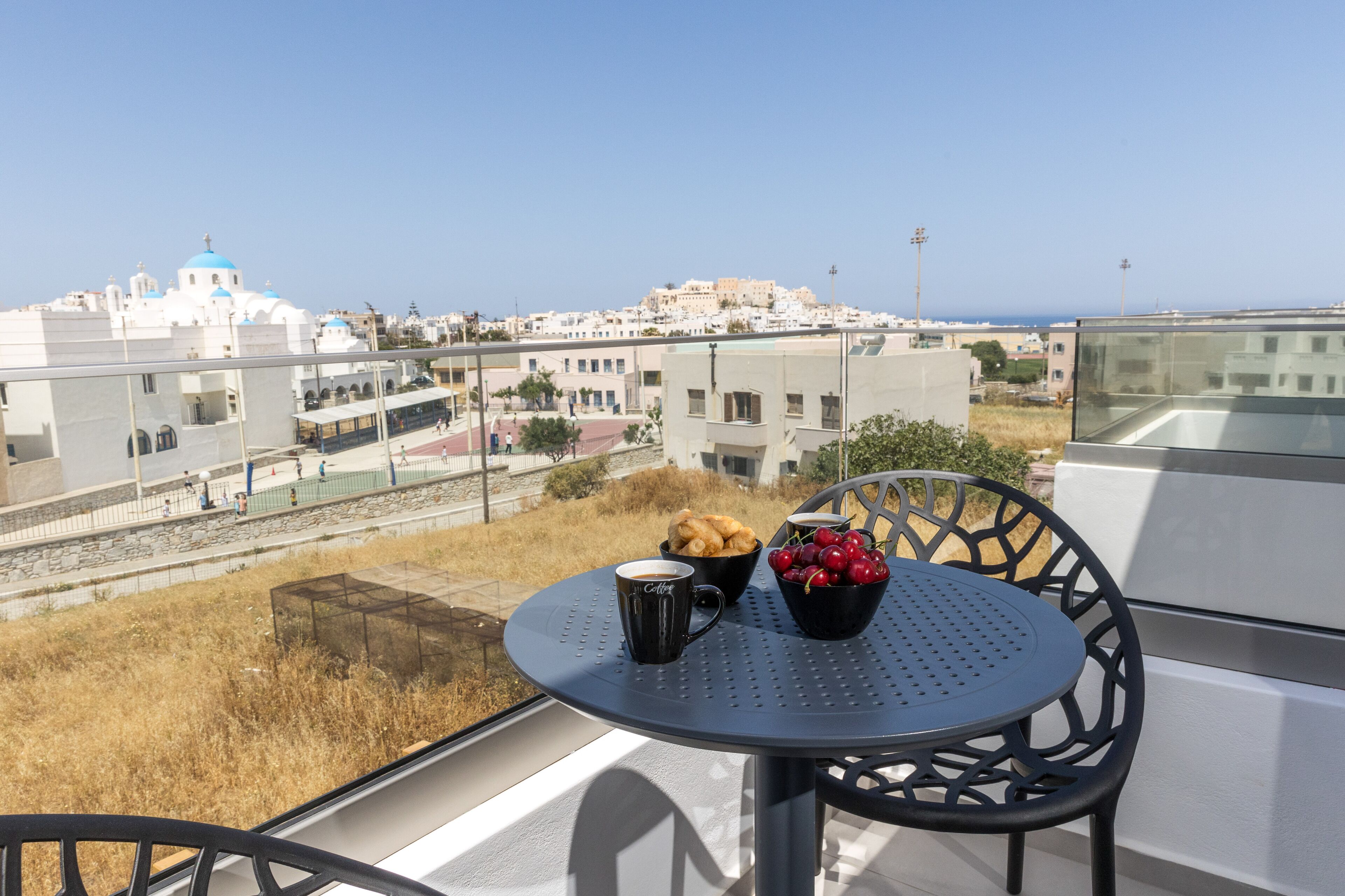 A balcony with a table and chairs, a bowl of fruit, and a cup.