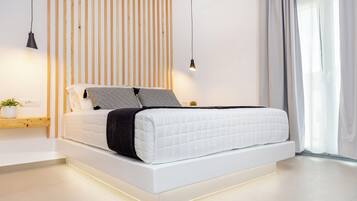 A modern bedroom with a white bed, a wooden slat wall, and a pendant light.