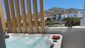 A hot tub with a wooden fence and a view of a hillside with buildings. - Alenor City Hotel (Naxos)