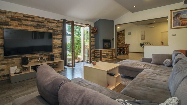 Ein modernes Wohnzimmer mit großem Flachbildfernseher, Kamin und gemütlicher Sitzecke.