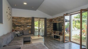 Ein modernes Wohnzimmer mit Ecksofa, Couchtisch, Flachbildfernseher und Wand mit Steinmuster.