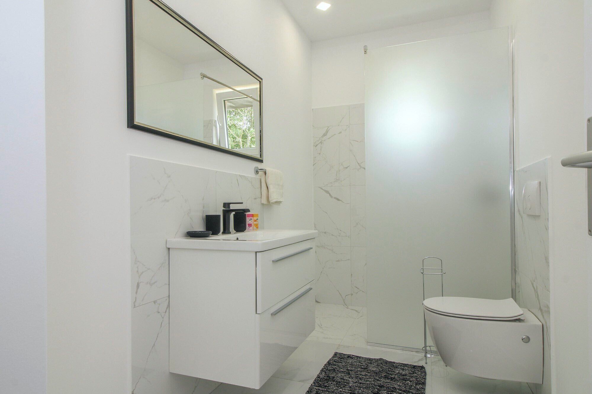 Un bagno moderno con un mobile lavabo bianco, un water e un box doccia.
