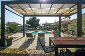 A covered outdoor area with a pool, lounge chairs, and a table. - Mani in Pilkovići - Istria / Mani in Pilkovići - Apartment for 6 people (Kanfanar)