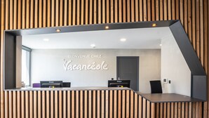 Un comptoir d’accueil au design moderne, agrémenté d’un mur en panneaux de bois et d’un grand miroir.