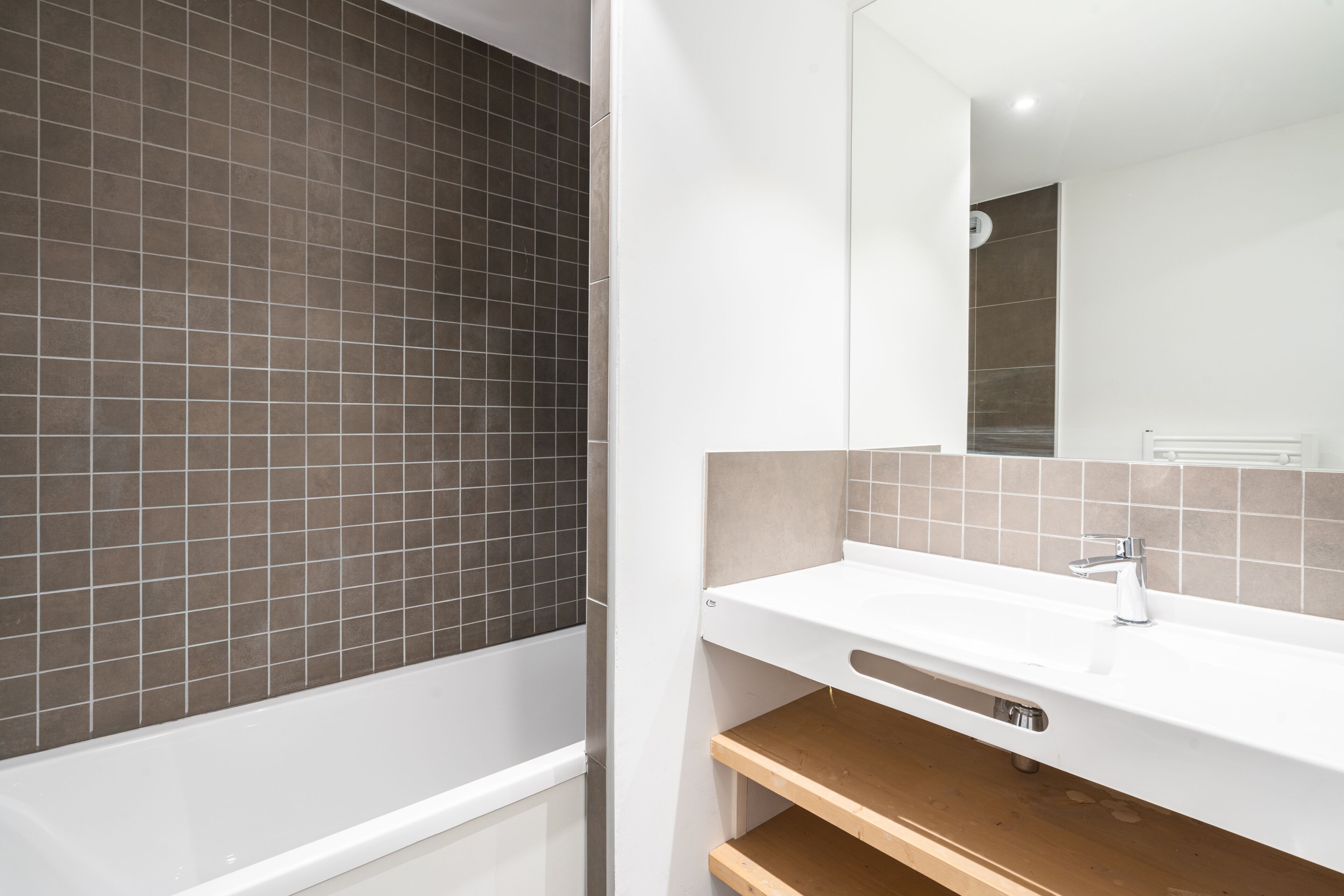 A modern bathroom with a bathtub, a white sink, and a mirror.