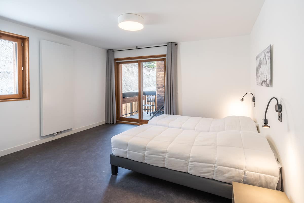 Une chambre à coucher avec un lit, une fenêtre, une porte et une vue sur un espace extérieur.