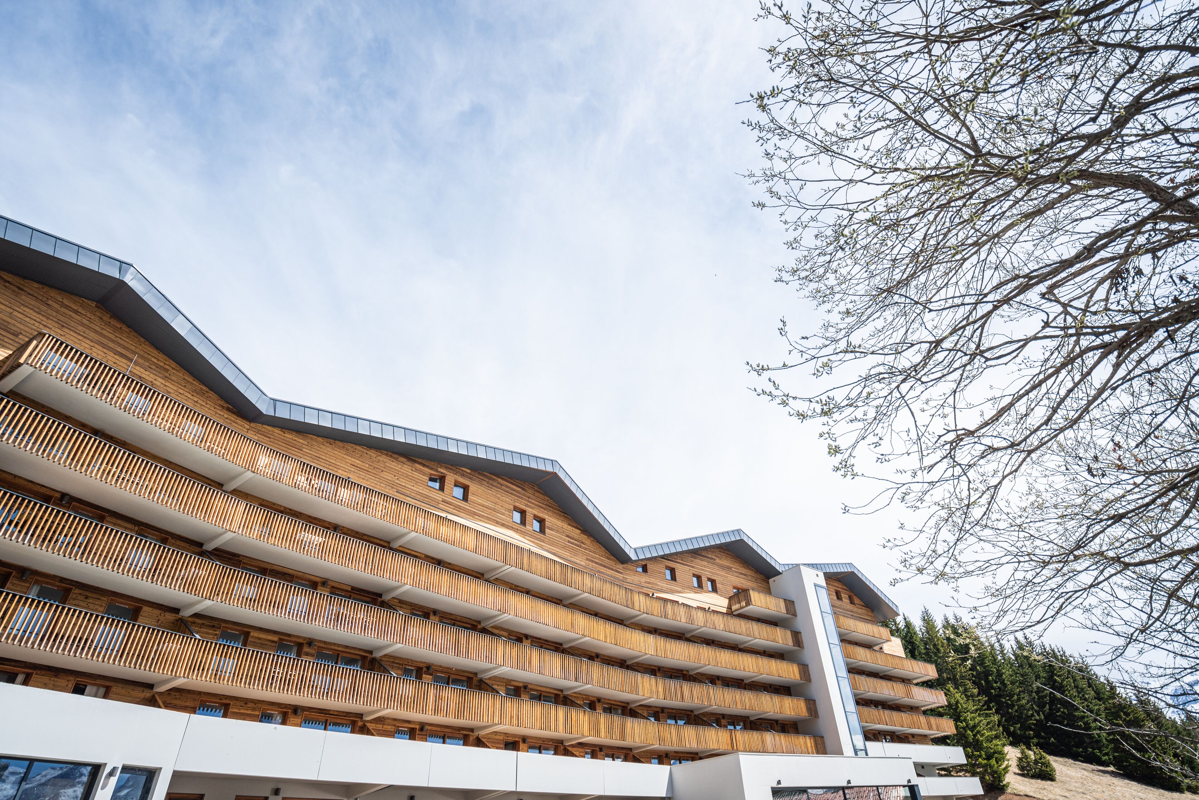 A multi-story hotel with wooden balconies and a modern architectural design.