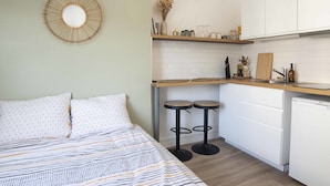Une cuisine compacte comprenant un lit, un miroir rond et un petit coin repas.
