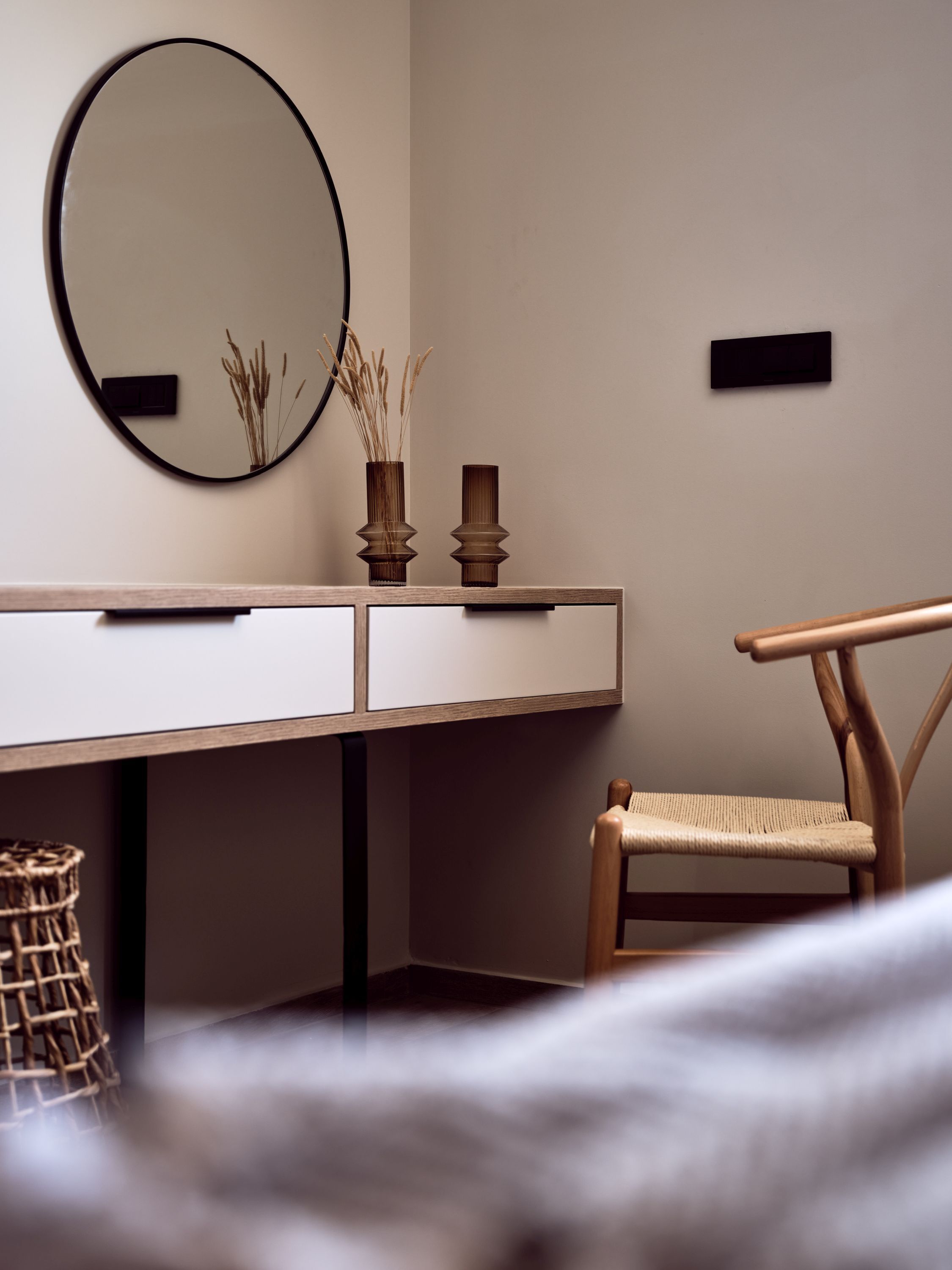 A modern bedroom with a wooden bed, a bedside table with a mirror, and a chair.