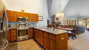 A modern kitchen with wooden cabinets, stainless steel appliances, and a large island.