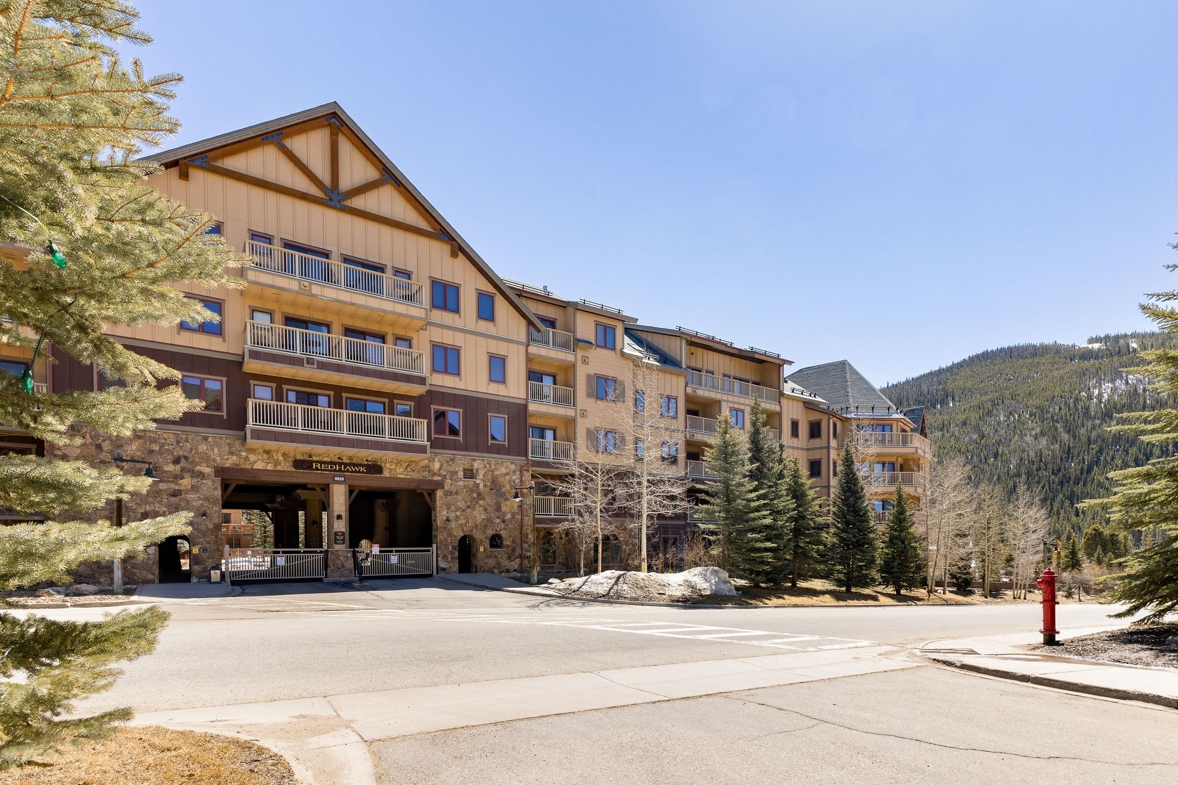 A multi-story hotel with a stone facade, balconies, and a mountainous backdrop.