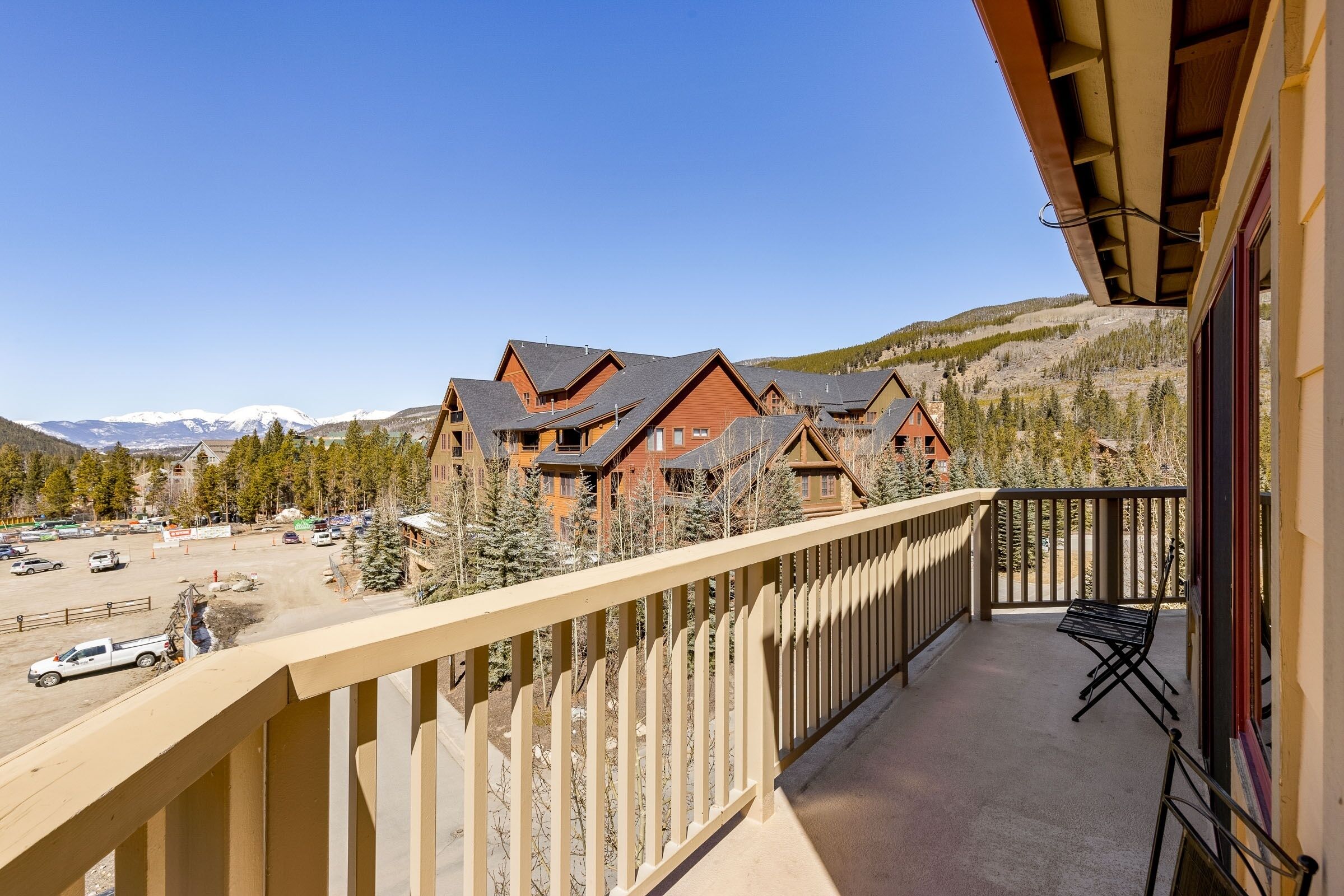 Un balcon avec vue sur une chaîne de montagnes et un parking.