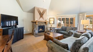 A living room with a stone fireplace, a television, a sofa, and a dining area.